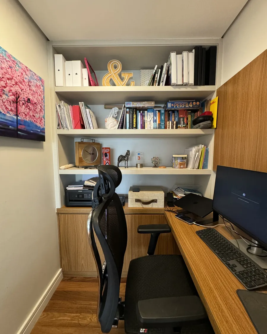 Escritório integrado à sala, com marcenaria e estante