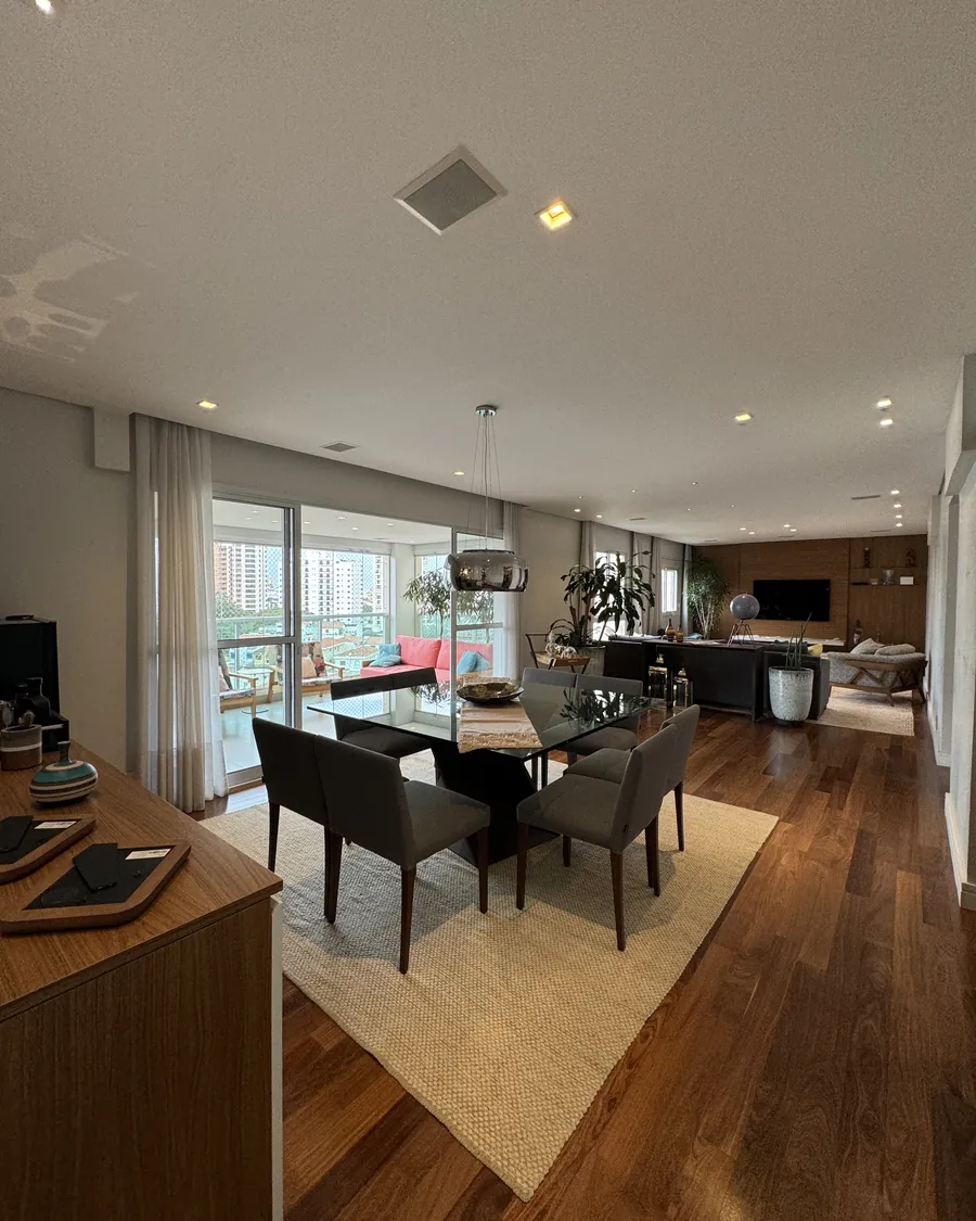 Sala de jantar com piso de madeira e vista para a varanda
